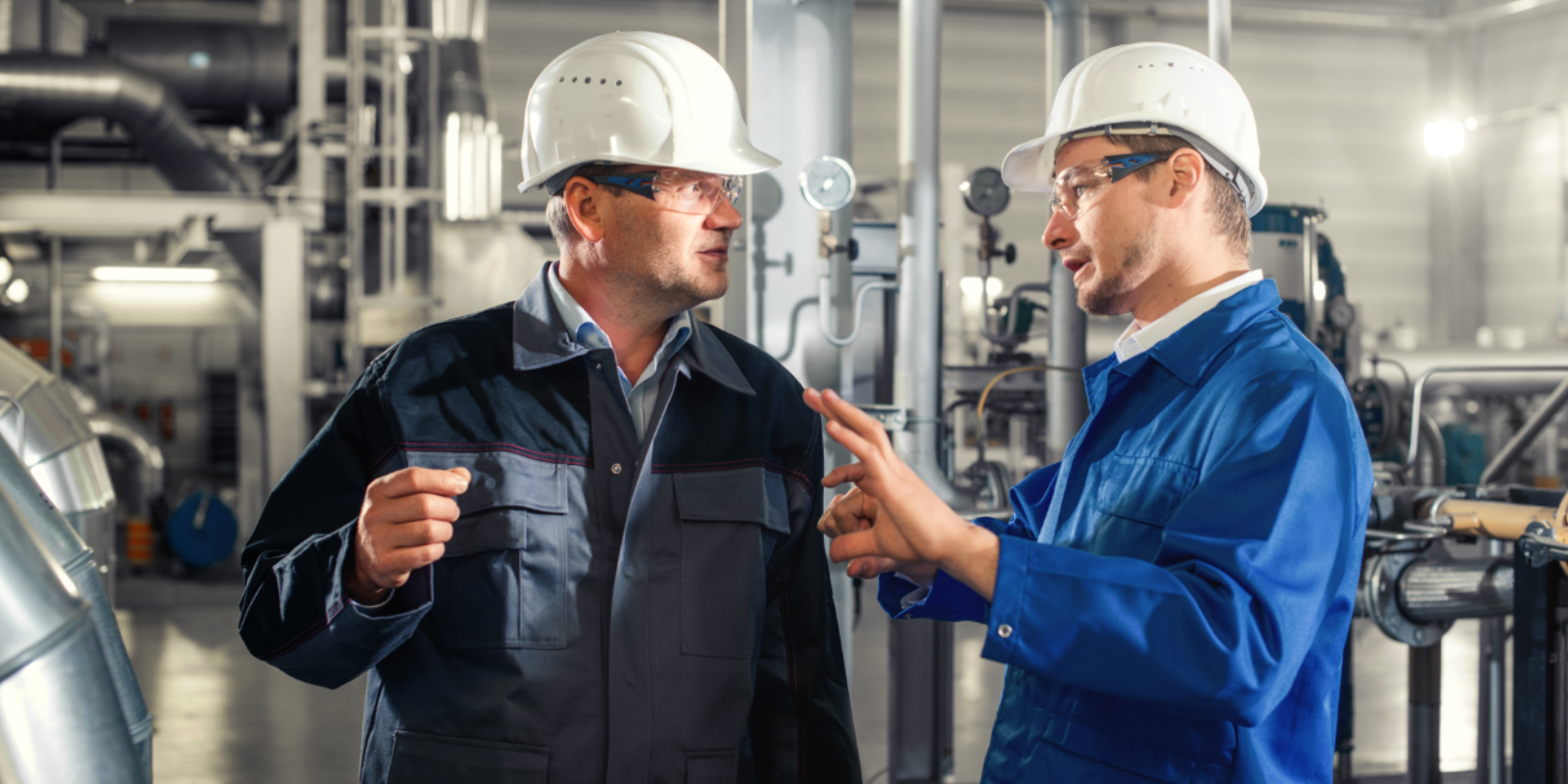 two men discuss in front of a machine two men discuss in front of a machine